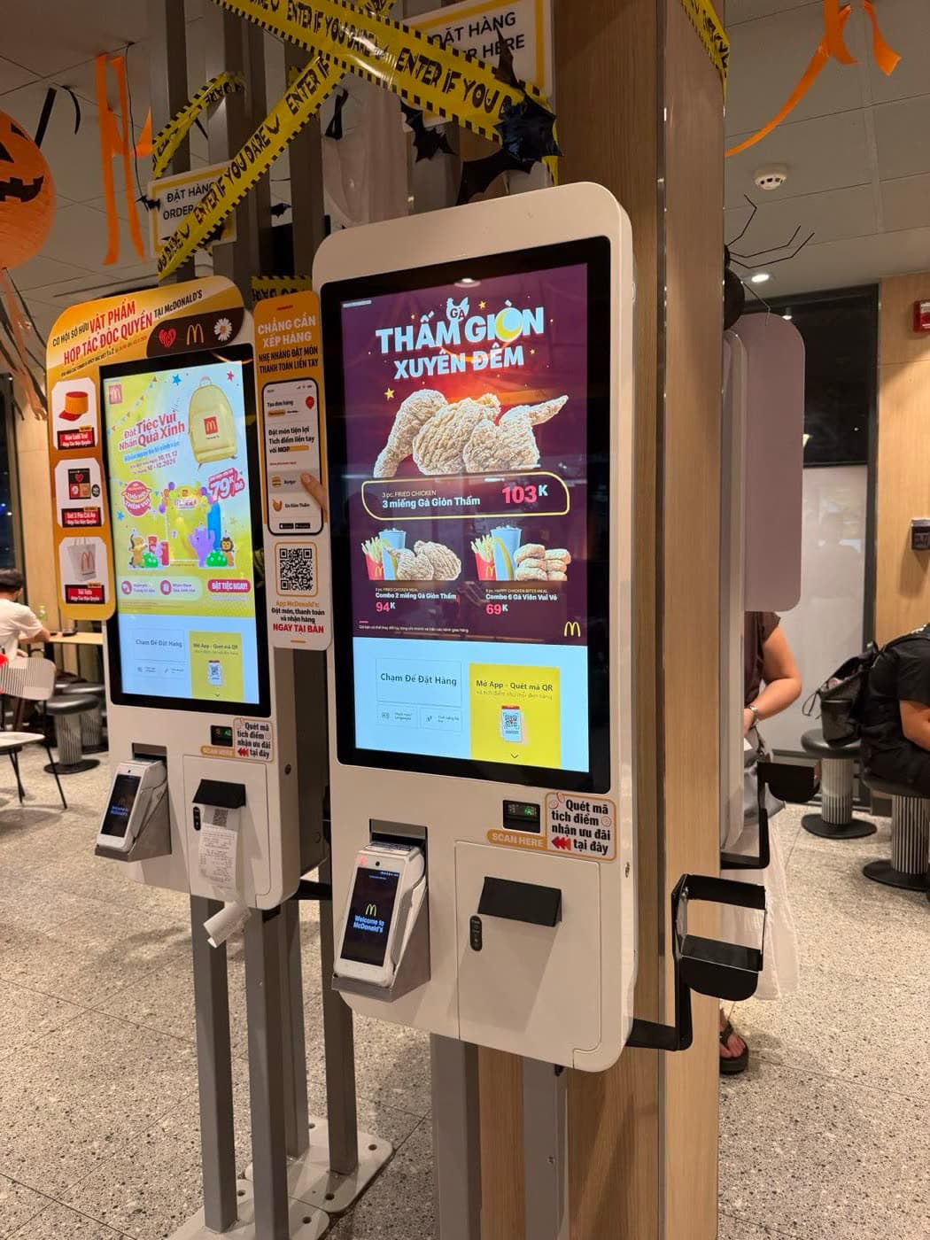 Two wall-mounted self-ordering kiosks with a touchscreen, card reader and receipt printer